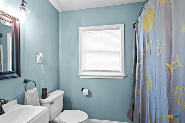 bathroom featuring baseboards, toilet, a sink, and curtained shower