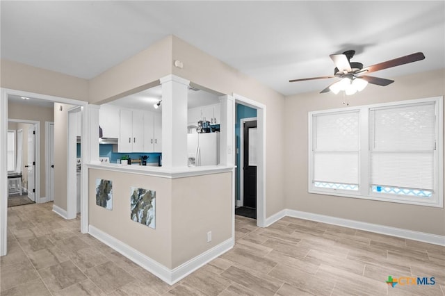 kitchen with a ceiling fan, white fridge with ice dispenser, light countertops, baseboards, and white cabinetry