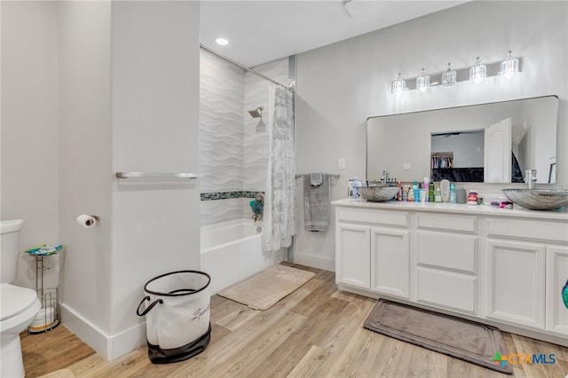 full bathroom with hardwood / wood-style floors, vanity, shower / tub combo, and toilet