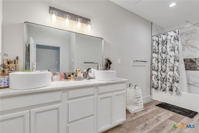 bathroom with shower / bath combo with shower curtain, wood-type flooring, and vanity