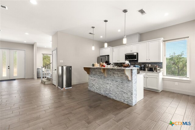 kitchen featuring white cabinetry, plenty of natural light, a kitchen island with sink, and appliances with stainless steel finishes