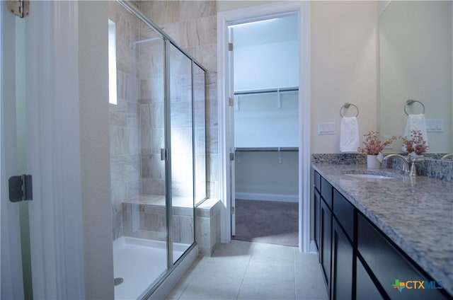 full bath with a spacious closet, a shower stall, tile patterned floors, and vanity