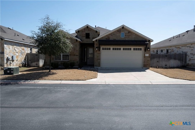 view of front of property with fence, central AC unit, a garage, stone siding, and driveway