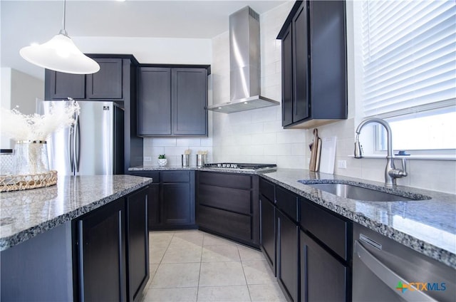 kitchen with backsplash, appliances with stainless steel finishes, stone countertops, wall chimney exhaust hood, and a sink