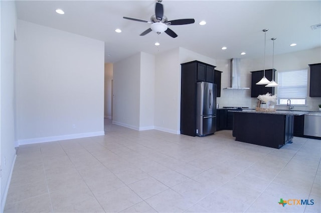 kitchen featuring stainless steel appliances, backsplash, a ceiling fan, and wall chimney range hood