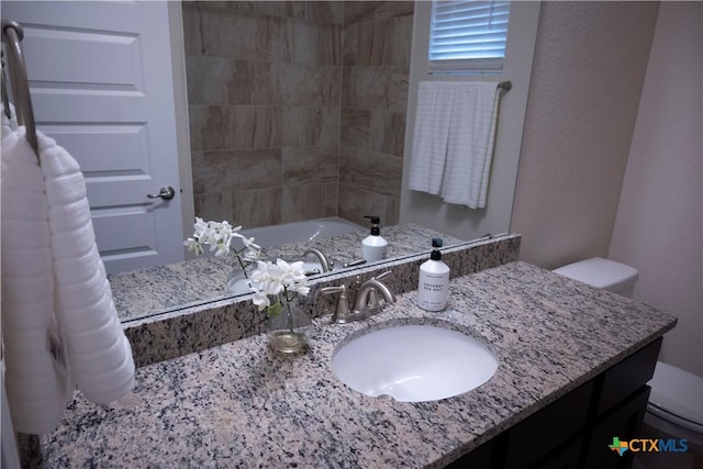 bathroom featuring vanity, toilet, and a washtub