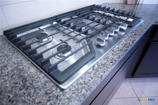 room details featuring tasteful backsplash, dark stone counters, and stainless steel gas stovetop