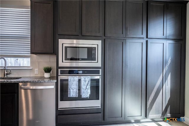 kitchen with a sink, decorative backsplash, stone countertops, and stainless steel appliances