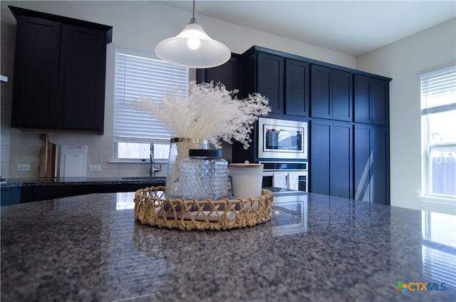 kitchen with dark stone countertops, plenty of natural light, appliances with stainless steel finishes, and a sink