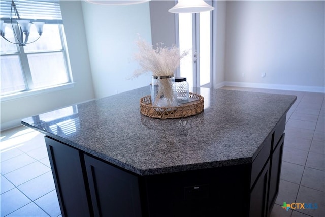 kitchen with decorative light fixtures, a center island, dark stone counters, an inviting chandelier, and tile patterned flooring