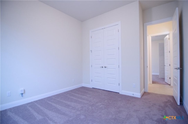 unfurnished bedroom featuring a closet, baseboards, and carpet flooring