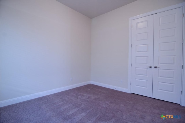 empty room featuring carpet and baseboards