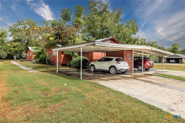 view of vehicle parking with a yard and a carport