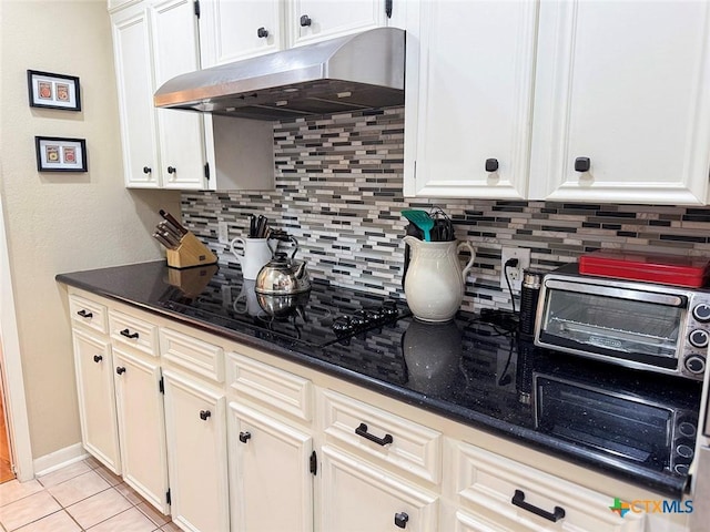 1802 Plantation Rd, Victoria, TX 77904 - kitchen with under cabinet range hood, tasteful backsplash, dark stone counters, and light tile patterned flooring