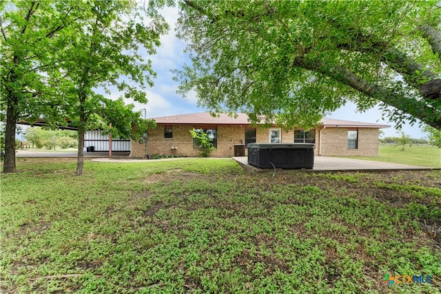 back of house with a hot tub, a patio, and a yard