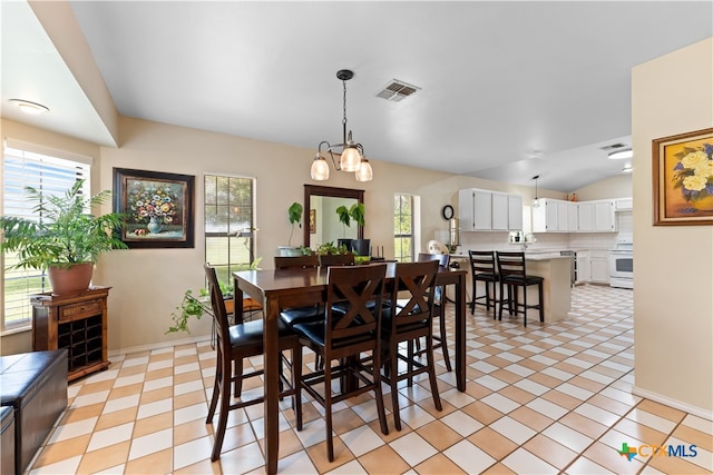 dining room featuring lofted ceiling, a chandelier, sink, and light tile patterned floors