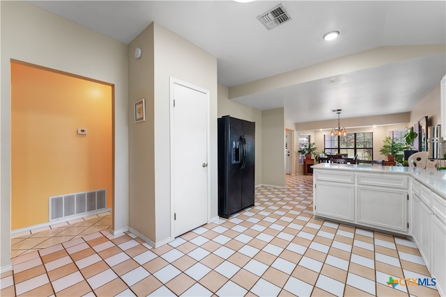 kitchen with white cabinets, kitchen peninsula, a notable chandelier, black fridge with ice dispenser, and pendant lighting