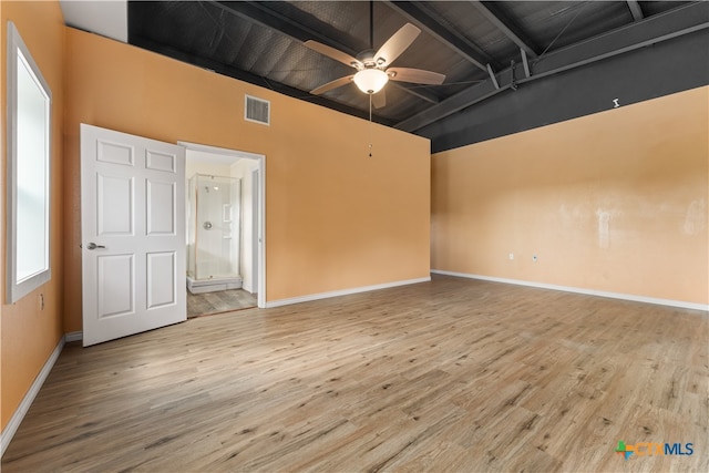 empty room featuring beamed ceiling, ceiling fan, and light wood-type flooring