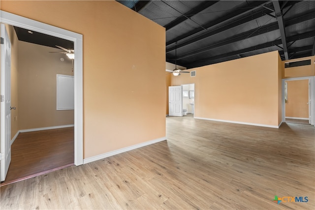 unfurnished living room featuring a towering ceiling, hardwood / wood-style flooring, and ceiling fan