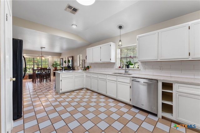 kitchen featuring a wealth of natural light, stainless steel dishwasher, decorative light fixtures, and black refrigerator