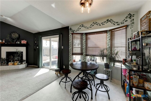 dining area featuring light carpet, a brick fireplace, and lofted ceiling