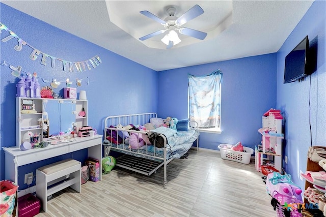 bedroom with a textured ceiling, hardwood / wood-style flooring, and ceiling fan