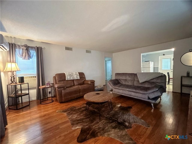 living room featuring wood finished floors, visible vents, and a wall mounted air conditioner