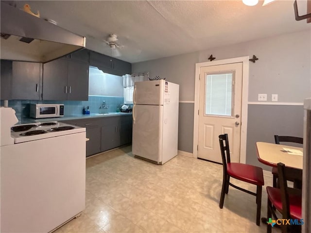 kitchen with decorative backsplash, light floors, white appliances, and a sink