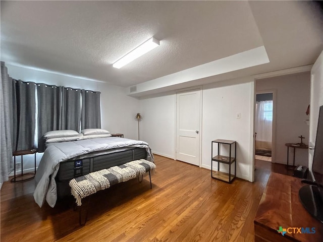 bedroom with light wood-type flooring, a textured ceiling, and visible vents