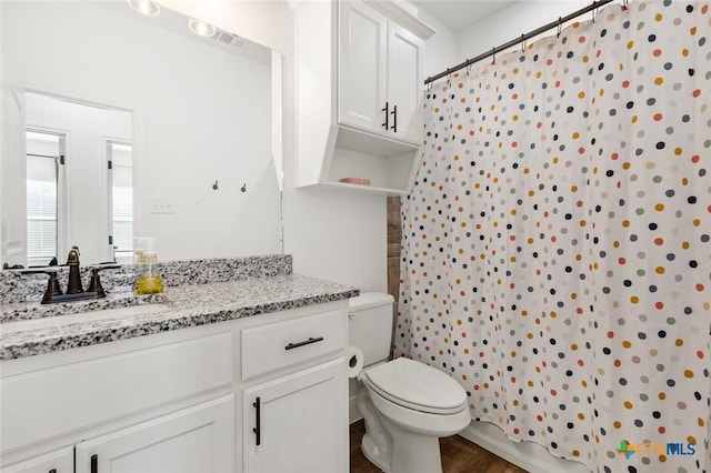 bathroom featuring wood-type flooring, toilet, vanity, and walk in shower