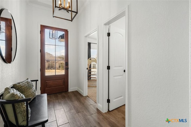 doorway to outside with crown molding, a chandelier, and light wood-type flooring