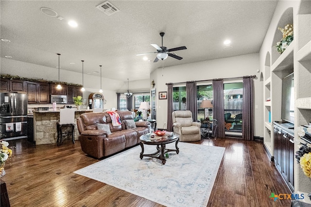 living area with dark wood finished floors, visible vents, a ceiling fan, and a textured ceiling