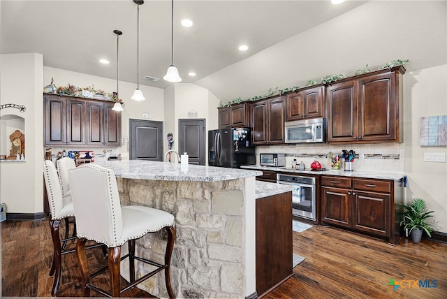 kitchen featuring stainless steel appliances, a kitchen bar, tasteful backsplash, dark wood-type flooring, and dark brown cabinets