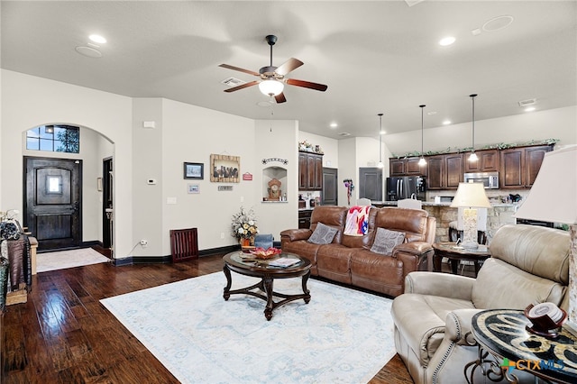 living room featuring recessed lighting, arched walkways, baseboards, a ceiling fan, and dark wood-type flooring