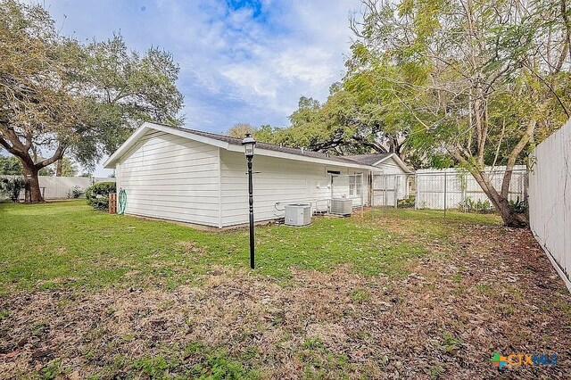 back of property featuring a fenced backyard, central AC, and a yard