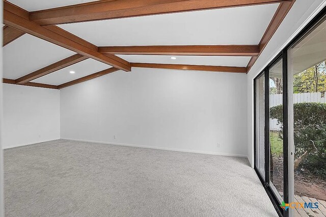 carpeted empty room with vaulted ceiling with beams and baseboards