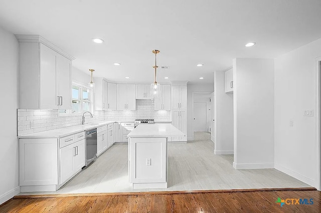 kitchen with dishwashing machine, backsplash, light countertops, and white cabinetry