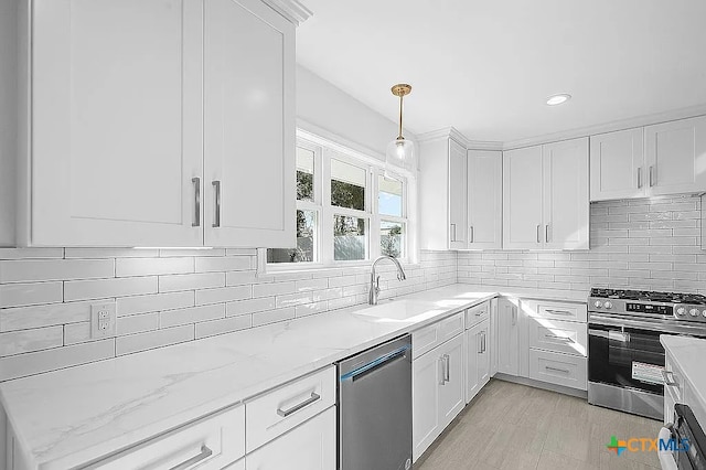 kitchen featuring backsplash, light stone countertops, appliances with stainless steel finishes, white cabinets, and a sink