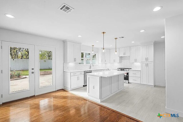 kitchen with visible vents, tasteful backsplash, white cabinetry, appliances with stainless steel finishes, and light countertops