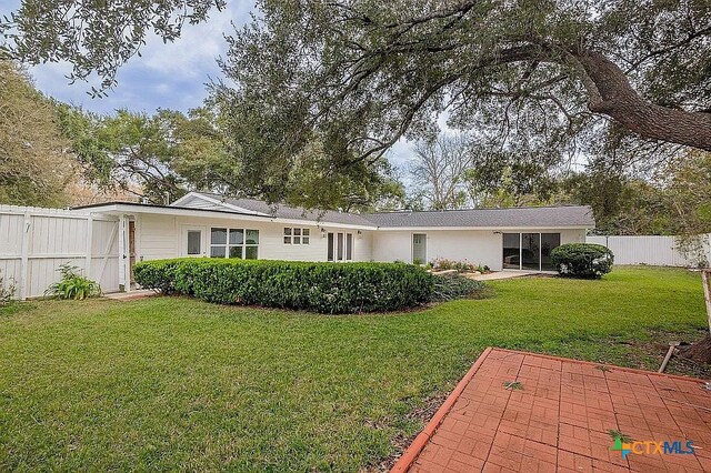 back of house featuring a yard, a patio, and fence