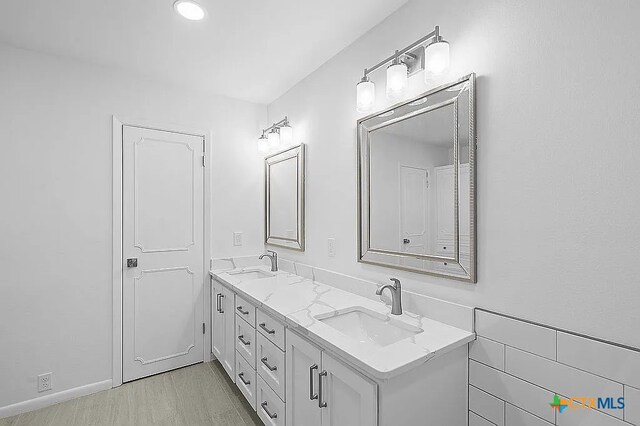 full bathroom featuring double vanity, wood finished floors, and a sink