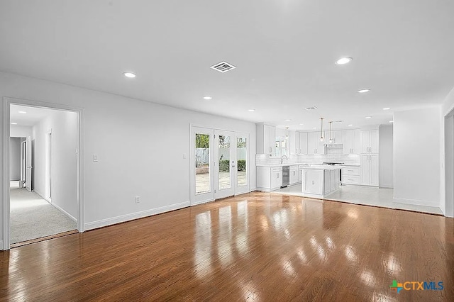 unfurnished living room featuring visible vents, recessed lighting, french doors, light wood finished floors, and baseboards