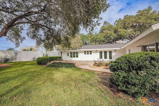 rear view of house with a patio, a lawn, and fence