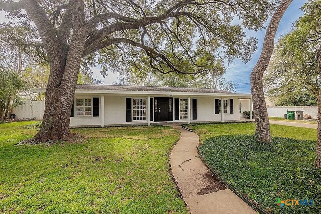 ranch-style house featuring stucco siding, a front yard, and fence