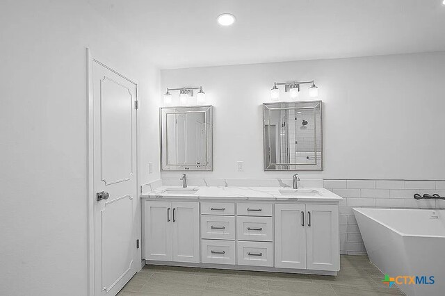 bathroom featuring a sink, a freestanding bath, and double vanity