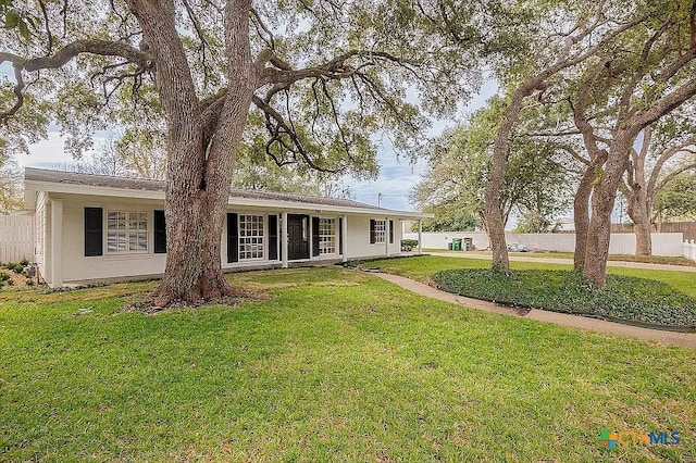 view of front of home with stucco siding, a front yard, and fence