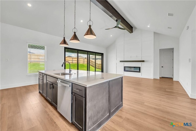 kitchen with a wealth of natural light, light hardwood / wood-style flooring, beamed ceiling, and stainless steel dishwasher