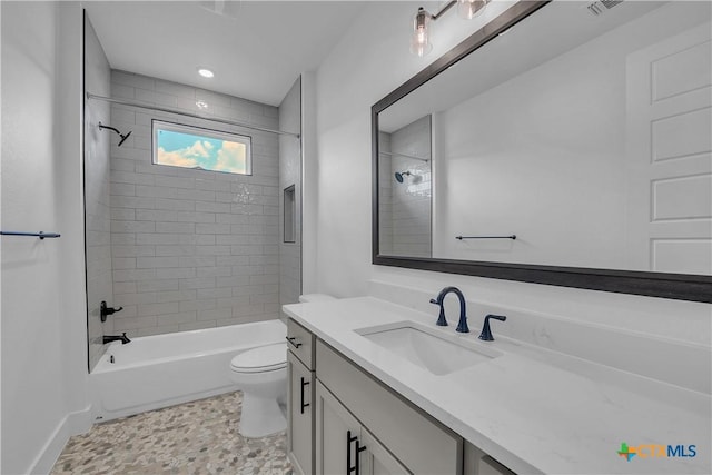 full bathroom featuring tile patterned flooring, vanity, tiled shower / bath combo, and toilet