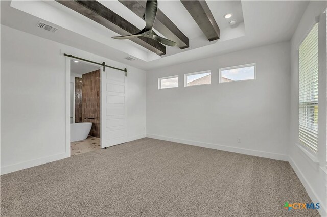 carpeted empty room featuring a barn door, ceiling fan, plenty of natural light, and beamed ceiling