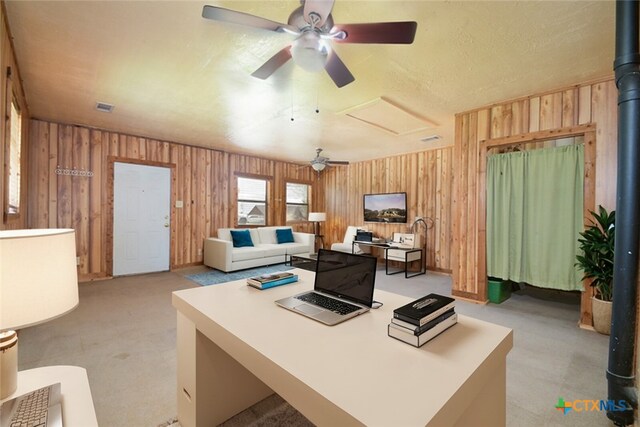 carpeted office with ceiling fan and wood walls